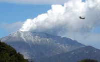 噴煙が上がる御嶽山と自衛隊のヘリコプター（30日午前、長野県王滝村）