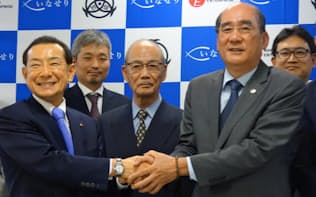 握手を交わす伊藤東卸理事長(右)と日本エンタープライズの植田勝典社長(左)
