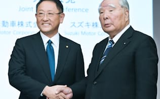 握手する豊田章男社長(左)と鈴木修会長（12日、東京都文京区）
