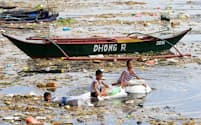 海上に浮かぶプラスチックごみを回収する子どもたち（17年10月、フィリピンのマニラ湾）=ロイター
