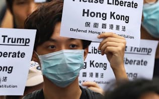 デモ参加者は「トランプ大統領、香港を解放してください」と書かれたプラカードを掲げた（26日、香港）=ロイター
