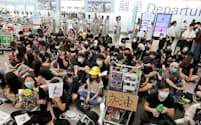 13日、香港国際空港の出発ゲート前に座り込むデモ参加者=ロイター
