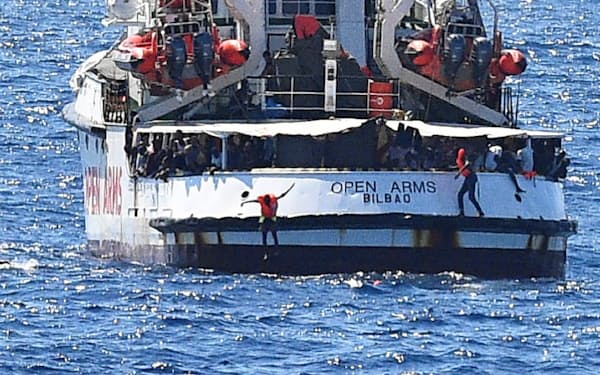 スペインの救助船から海に飛び込む移民（20日、イタリア南端ランペドゥーザ島付近）=ロイター
