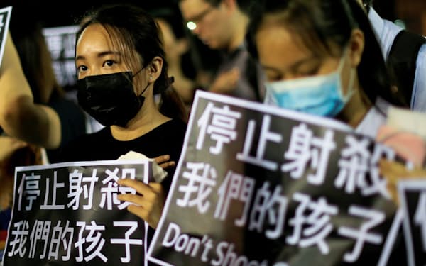 「私たちの子どもを撃つな」と書かれた紙を掲げる人たち（2日、香港）=ロイター
