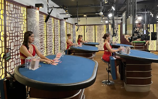 無人のテーブルにカードを配るオンラインカジノに勤める女性たち=クリフ・ベンゾン撮影
                                                        