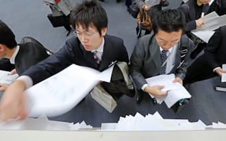 6日、東証で決算発表資料を配布する企業の担当者ら