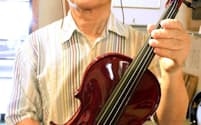 漆を用いたバイオリンを手にする輪島塗の職人八井汎親さん（石川県輪島市）