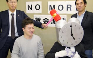 ポーズを取る「NO MORE　賃金泥棒」プロジェクト呼び掛け人の佐々木弁護士(左)ら（東京都内）