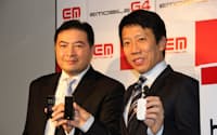 「D41HW」と「HTC Aria」を手に持つイー・モバイルのエリック・ガン社長（右）と台湾HTCの日本法人、HTC Nipponのデビッド・コウ社長