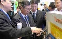 中国ZTEのブースで「CDMA2000 EV-DO」方式も使えるタブレット端末の説明を受けるKDDIの小野寺社長（左から2人目）