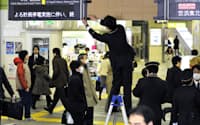東京電力の計画停電に合わせ大幅にダイヤを変更し、運休が決まった路線の電光板に目張りをする駅員（14日午前、JR新宿駅）=共同
