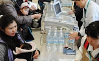 優先販売でペットボトルのミネラルウォーターを購入する1歳未満の子どもを持つ母親たち(24日、東京都江東区のイトーヨーカドー木場店)