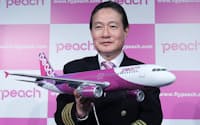 ブランド名「Peach」をデザインした機体の模型を手にするエーアンドエフ・アビエーションの井上慎一CEO(24日午前、大阪市北区)