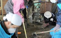 民家の倉庫にたまった泥をかき出す、県外からきたボランティア(2011年5月3日、宮城県七ケ浜町)