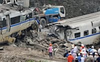 事故発生後、高架橋から地面に下ろされた高速鉄道の車両(左)。追突した車両の先頭とみられる一部(中央下)は一時地中に埋められた（7月24日、中国浙江省温州市）=共同