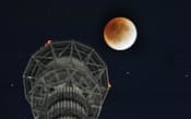 東京スカイツリー上空に浮かぶ皆既月食の月(10日、東京都墨田区)
