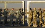 18日、イラクから撤退した駐留米軍の最後の車両がクウェートに入った後、クウェート側で国境のゲートを閉める兵士ら=ロイター