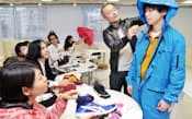 健常者と障害者が共に着用できるコートの説明をする須藤シンジさん(中央、東京都渋谷区のアシックスのオフィス)