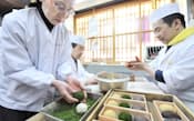 手作りで一つずつおはぎに青のりをまぶしていく祇園饅頭の工場(京都市東山区)