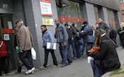 スペインのマドリードで失業給付に列をつくる人々=AP