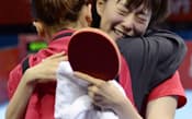 卓球女子団体でシンガポールを破り決勝進出を決め、福原(手前)と抱き合う石川=共同