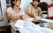 「ツタエテガミプロジェクト」の活動で、被災者に手紙を書く早瀬友季子さん(左)=8月、神戸市東灘区