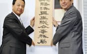 「日本経済再生総合事務局」の看板を掛ける安倍晋三首相（右）と甘利明経済再生担当相（1月7日午前、内閣府）=代表撮影