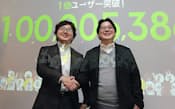 「LINE」の利用者数が1億人を突破し、握手するNHNジャパンの森川社長(左)と舛田執行役員(1月18日午後、東京都渋谷区)