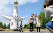 万博記念公園でモニュメント「太陽の塔」をバックに記念撮影する人たち(大阪府吹田市)