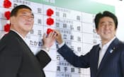 当選のバラを付ける自民党の石破幹事長(左)と安倍首相(21日夜、自民党本部)
