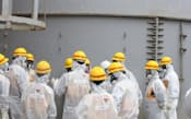 23日、福島第1原子力発電所で汚染水が漏れたタンクなどを視察する原子力規制委の委員ら