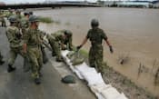 川の水が堤防を越えた桂川で土のうを積む自衛隊員(16日午前、京都市伏見区)