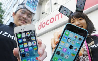 iPhone5s(左)と同5cを手に笑顔を見せる人たち(20日、東京都千代田区)