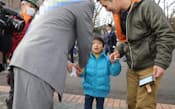 多摩動物公園前で、家族連れに支持を訴える都知事選の立候補者(26日、東京都日野市)=一部画像処理しています