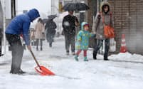 降り積もる雪の中、除雪をする人(8日、東京都杉並区)