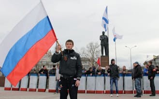 2日、ウクライナ南部クリミア自治共和国シンフェロポリの広場で、ロシア国旗を振る若者=共同
