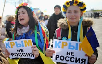 14日、ウクライナ南部シンフェロポリで「クリミアはロシアではない」との紙を掲げて16日に行われる住民投票に反対の意思表示をする女性たち=ゲッティ共同