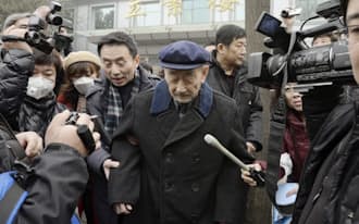 強制連行をめぐり提訴後、報道陣に囲まれる被害者の男性(2月26日、北京市の第1中級人民法院前)=共同