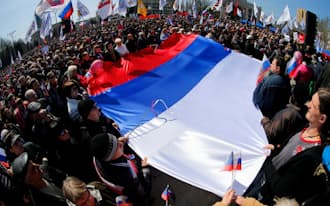 6日、ウクライナ東部ドネツク州庁舎前で、ロシア国旗を広げる親ロシア派デモ隊=AP