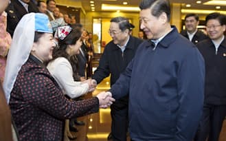 4月30日、中国新疆ウイグル自治区ウルムチを訪れ、地元の労働者らと握手する習近平国家主席（右）=新華社共同