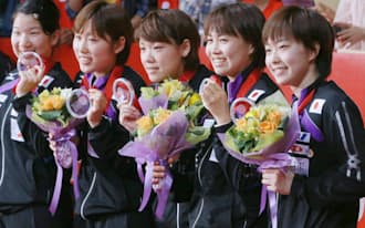 卓球世界選手権の団体戦で準優勝し、銀メダルを手に笑顔を見せる石川佳純（右）ら日本女子代表（5日、東京・国立代々木競技場）