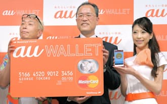 電子マネー「au WALLET(ウォレット)」を発表したKDDIの田中社長（中）。クレジットカードのようなカードを発行し、スマホの専用アプリなどで入金できるようにした(8日午後、東京都港区)