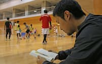フットサルの試合の合間に読書する参加者の男性(東京都中央区の中央区総合スポーツセンター)