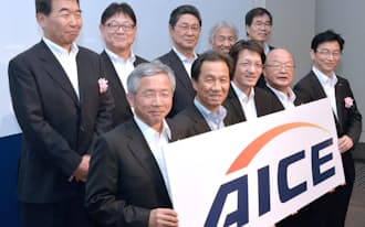 AICE設立の記者会見でロゴマークと記念写真に納まる関係者(5月19日、東京都港区)