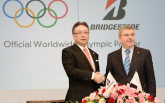 調印式で握手するブリヂストンの津谷CEO兼会長(左)とIOCのバッハ会長(13日午後、東京都千代田区)