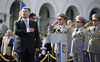 独立記念日の軍事パレードで国歌を斉唱するウクライナのポロシェンコ大統領=左（8月24日、キエフ)=ロイター