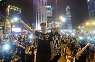 香港の次期行政長官選挙をめぐる中国の決定に抗議し、政府庁舎近くの幹線道路で携帯電話を掲げるデモ参加者(1日夜、香港・金鐘地区)=共同 香港の次期行政長官選挙をめぐる中国の決定に抗議し、政府庁舎近くの幹線道路で携帯電話を掲げるデモ参加者(1日夜、香港・金鐘地区)=共同