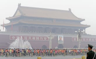 北京マラソンでは深刻な大気汚染でかすむ天安門の前を大勢の参加者が走り抜けた（10月19日）=共同