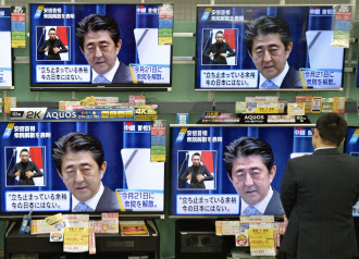 足を止めて安倍首相の会見模様に見入る人(18日夜、東京・新橋の家電量販店)=共同 足を止めて安倍首相の会見模様に見入る人(18日夜、東京・新橋の家電量販店)=共同