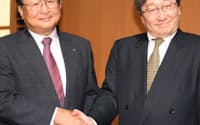 記者会見で握手するリコーの近藤社長(左)とHOYAの鈴木CEO（1日、東京都千代田区）